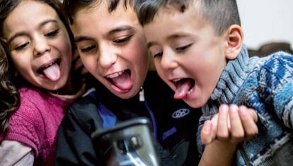 Tres niños se hacen una foto con un teléfono móvil.