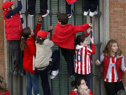 Niños encaramados a unas rejas para ver a los jugadores del Atlético