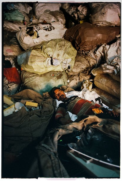 Un hombre descansa encima de los productos que usa en su taller, en la zona dedicada al reciclaje de plásticos en el barrio de Dharavi.