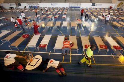 Voluntarios de Cruz Roja preparan camillas en el Pabellón Municipal de Deportes de Granadilla de Abona, para recibir hasta un total de trescientos desplazados por el incendio forestal que afecta al sur de Tenerife, y que se han visto obligados a abandonar sus hogares amenazados por el fuego y el humo.