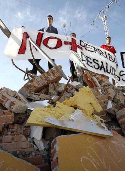 Varios manifestantes, sobre una de las casas derribadas.