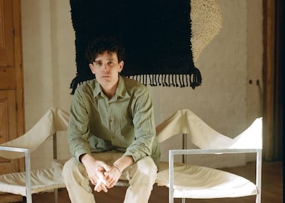 Jermaine Gallacher posa sentado en un banco de Lukas Gschwandtner, delante de su Wavy rug, en negro y crema, una tarde de febrero. |
