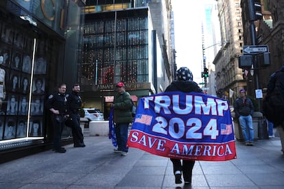 Una mujer camina por la Quinta Avenida con una bandera de apoyo al expresidente Donald Trump, el martes en Nueva York.