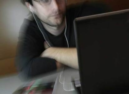 Un joven escucha música en su ordenador portátil.