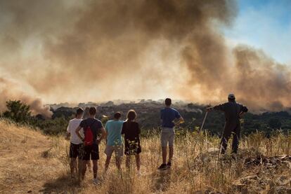 Un grupo de vecinos observa el incendio declarado en la localidad de Cualedro, en Ourense. Bomberos de Verín, brigadistas, Guardia Civil y vecinos se sumaron a las labores de extinción intentando proteger enseres y vehículos.