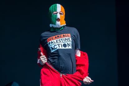 Arriba, DJ Próvaí, del grupo irlandés Kneecap, con una camiseta de Palestine Action en el pasado Festival de Glastonbury, en junio de 2025.
