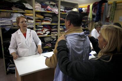 Las voluntarias del ropero de Cruz Roja en Alcorc&oacute;n (Madrid) entregan prendas para las familias enviadas por los servicios sociales.