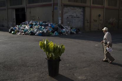 Un hombre pasa cerca de una pila de basura en el barrio del Pireo, Atenas. Hoy es el undécimo día de huelga de basuras, lo que está provocando enormes acumulaciones de deshechos alrededor de Atenas.