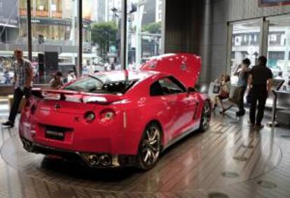 Varios turistas hacen fotos al nuevo modelo deportivo del Nissan GT-R en una exposición en Tokio (Japón).