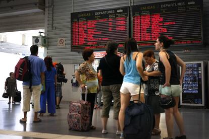 Viajeros consultando paneles informativos durante una operaci&oacute;n salida de vacaciones. 