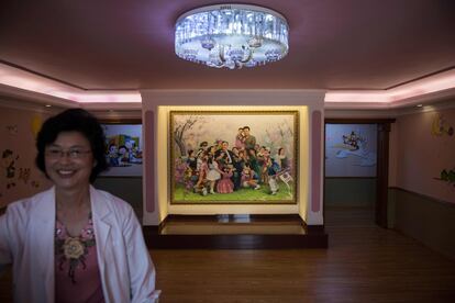 Una cuidadora de la guardería pasa junto a una pintura del fallecido líder norcoreano Kim Jong-Il.