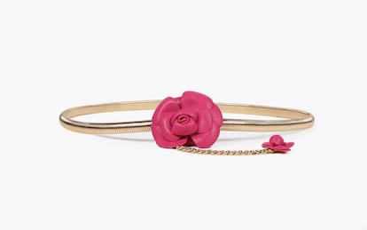 Lola Casademunt combina el metal dorado con el cuero en este original cinturón confeccionado en metal con elástico y una flor en rosa fucsia de efecto piel. Una fusión de estilos que es el toque especial de cualquier look de diario o como invitada de boda. (59.95 €)