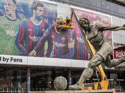 Operarios retiran a Messi de la facha del Camp Nou.