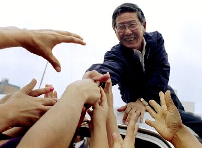 Alberto Fujimori, tendido sobre el techo de su vehículo, estrecha la mano de sus partidarios después de emitir su voto en las elecciones locales del 12 de noviembre de 1995.