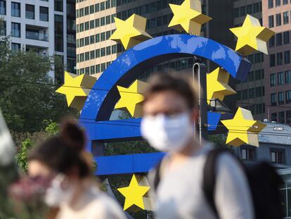 Dos personas pasean frente a un símbolo del euro cerca del cuartel general del BCE, en Fráncfort.