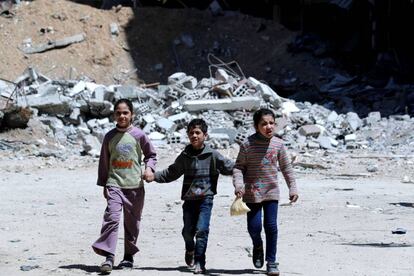 Tres niños caminan entre las ruinas de Duma.