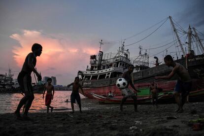 Niños juegan al fútbol en la orilla del río Yangon en Myanmar.