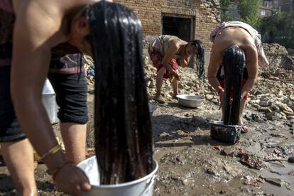 Unas mujeres se asean con cubos de agua cerca de las ruinas de sus casas en Bhaktapur (Nepal).