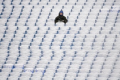 Un fantico del bisbol se sienta en las gradas cubiertas de nieve del estadio Highmark antes del partido entre los Atlanta Falcons y los Buffalo Bills, este domingo en Nueva York.