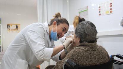 Una dentista examina la boca de una persona mayor.