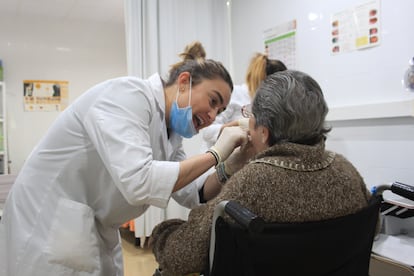 Una dentista examina la dentadura de una persona mayor.