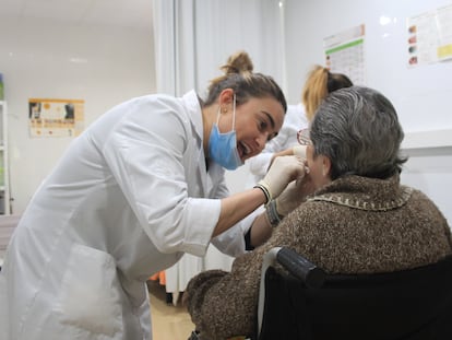 Una dentista examina la boca de una persona mayor.