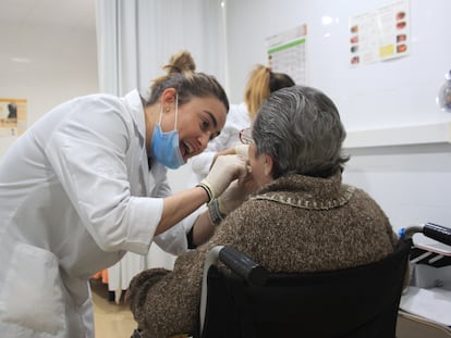 Una dentista examina la dentadura de una persona mayor.