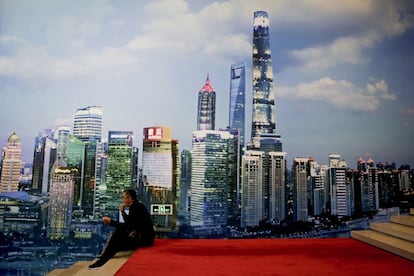 Un hombre come frente a un mural que representa los rascacielos de Shanghai, en el centro financiero de la ciudad china.