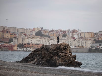 Un joven subido a una roca en la playa del Tarajal, el 22 de marzo;  al fondo, la ciudad de Ceuta.