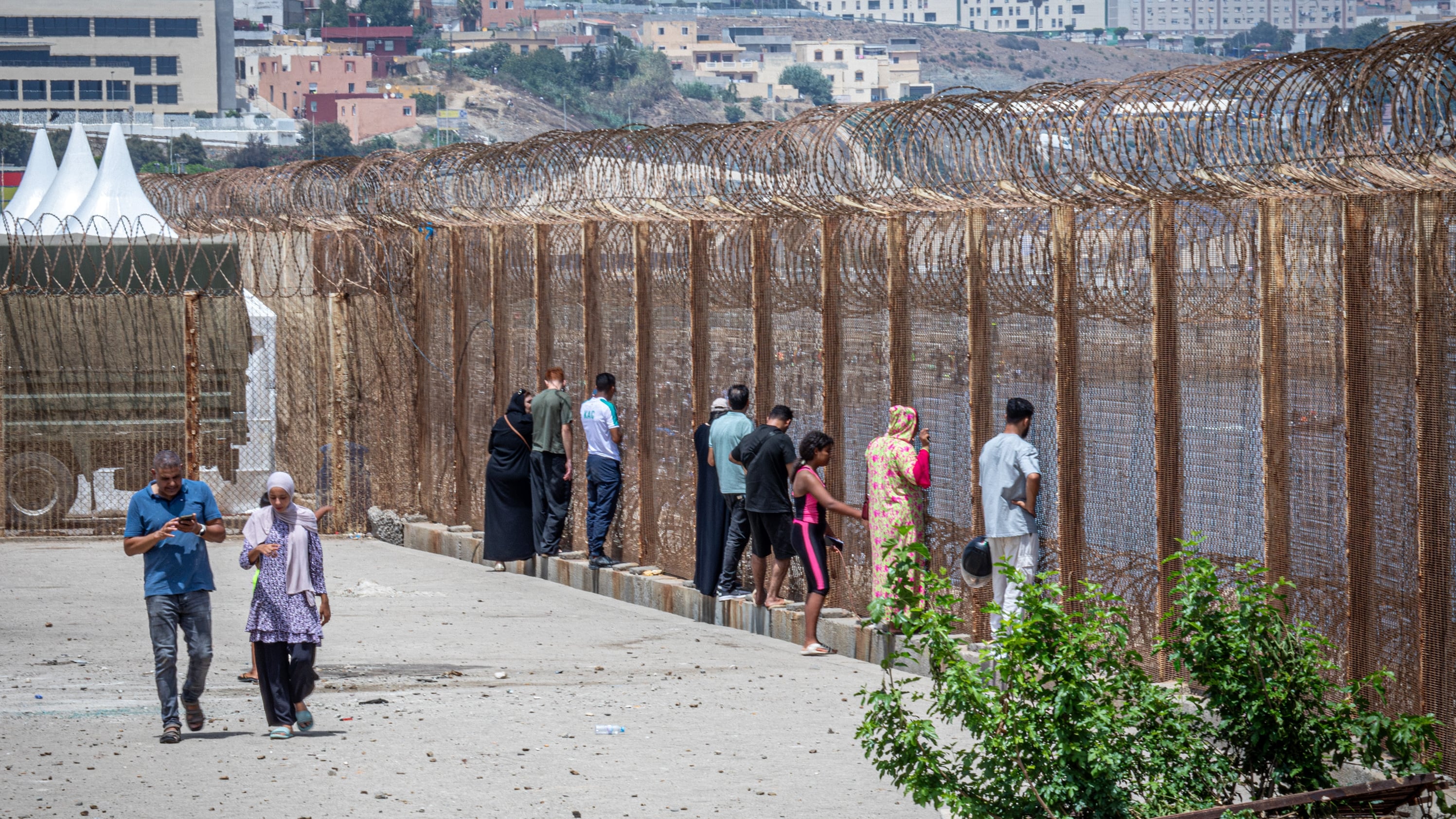 Familiares de jóvenes marroquíes que han cruzado a Ceuta sin haber vuelto aún esperaban su retorno este sábado en la valla de la frontera de Castillejos.