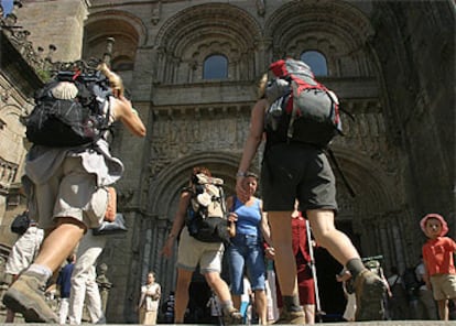 Un grupo de peregrinos se dirige a la puerta románica que da acceso a la catedral de Santiago de Compostela por la plaza de Platerías.