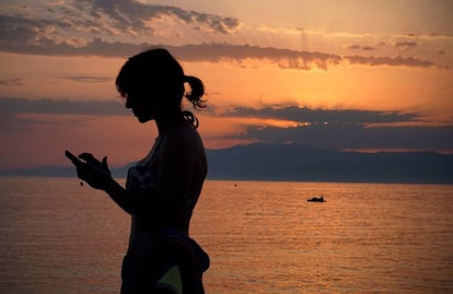 Una mujer revisa su teléfono móvil en la playa de Cabo de Gata en Almería, este verano.