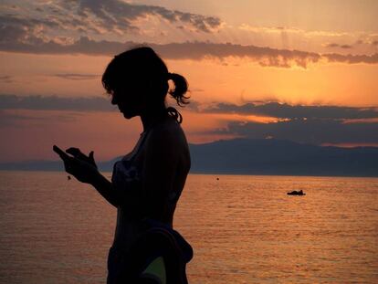 Una mujer revisa su teléfono móvil en la playa de Cabo de Gata en Almería, este verano.