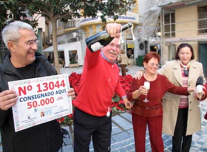 El quinto premio del sorteo de Navidad también fue hasta Málaga. Allí, la propietaria de la administración de la calle La Bolsa, de rojo y con gafas, festeja el premio junto a su marido y varios amigos.