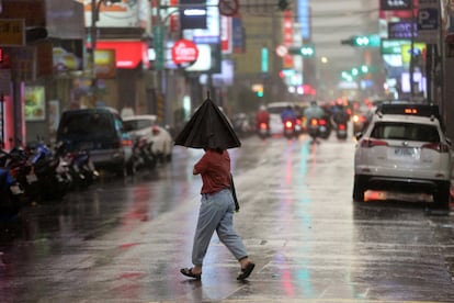 Una persona se enfrenta a fuertes vientos mientras cruza una calle en Taipei. Taiwán se prepara para el súper tifón María.