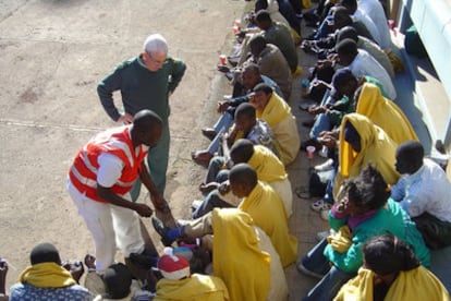 Un voluntario de Cruz Roja atiende a inmigrantes llegados a la localidad de Tajao, en Tenerife.