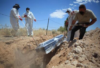 Trabajadores de una funeraria bajan un ataúd con una víctima de covid-19, en una zona asignada especialmente para decesos por el virus en el panteón San Rafael a 30 kilómetros de Ciudad Juárez, estado de Chihuahua (México).
