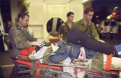 Médicos militares israelíes transportan en una camilla a una de las víctimas del atentado palestino.