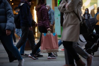 Viandantes caminan con bolsas por una vía de Barcelona, a 27 de diciembre de 2021 en Barcelona, Cataluña.