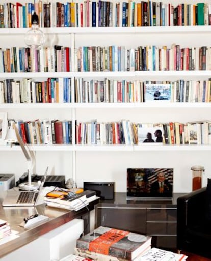 El despacho de Varoufakis en su casa. Además de su ordenador y un volumen sobre Warhol, en su librería se encuentra una foto junto a su esposa y una pieza de arte satírico con una ilustración de George W. Bush y la leyenda: “El mayor fracaso de América”.