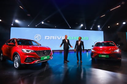 Directivos de MG posan junto a vehículos de la marca en el Salón del Automóvil de India 2023.