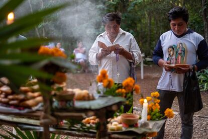 Maximiliano May Nahuat y su hijo, Domiliano rezan ante el altar. 
Juntos leen cantos religiosos mayas para que las almas se lleven la esencia de los alimentos ofrecidos.