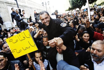 Unos manifestantes llevan en hombros a un policía en una protesta contra el partido de Ben Ali.
