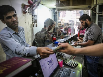 Unos sirios cambian la moneda local por liras turcas o dólares en una casa de cambio informal en la insurrecta provincia de Idlib.