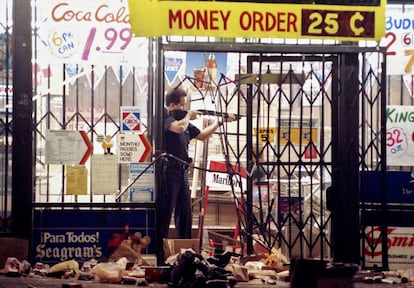 Un policía encañona a un ladrón en una tienda de alimentación de Los Ángeles, el 30 de abril de 1992, la segunda noche de disturbios.