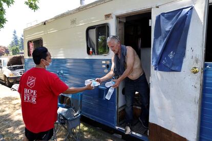 Un voluntario de Salvation Army entrega botellas de agua fría a un hombre que vive en una autocaravana sin aire acondicionado en Seattle. El calor extremo se cobra cada año la vida de al menos 600 estadounidenses.