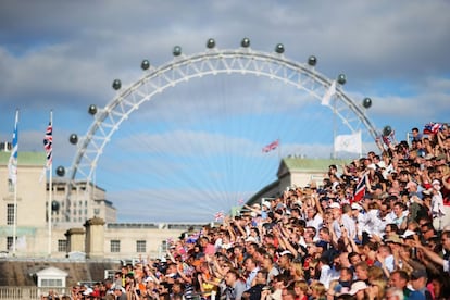 Fans see a beach volleyball game. In the background, the London Eye.
