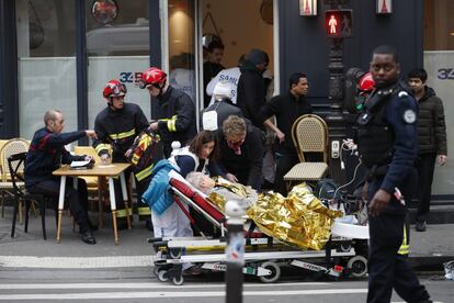 Personal médico atiende a un hombre herido en la explosión de la panadería de París. La calle en la que se produjo la explosión estaba cubierta de escombros y las llamas salían de la planta baja del edificio.