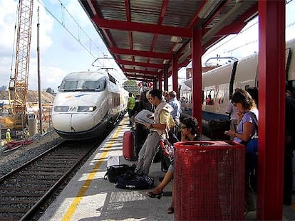 Los pasajeros atrapados por la avería en la estación de El Prat. A la izquierda, el tren que los recogió; a la derecha, el averiado.