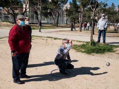 Un jugador realiza su lanzamiento durante una partida de petanca en el parque de Aluche.